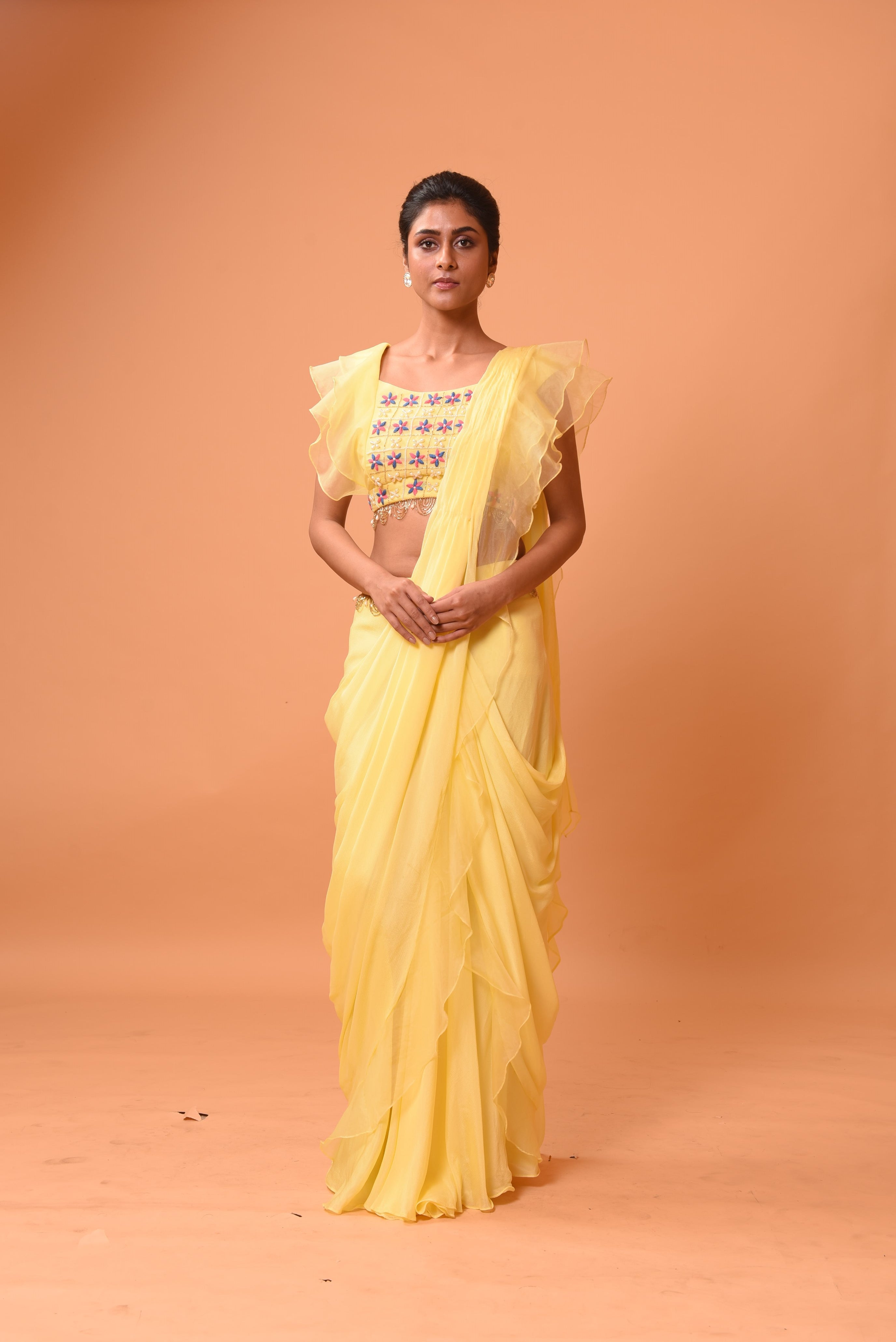 Yellow ruffle saree with lace work and embroidered blouse featuring intricate handwork.