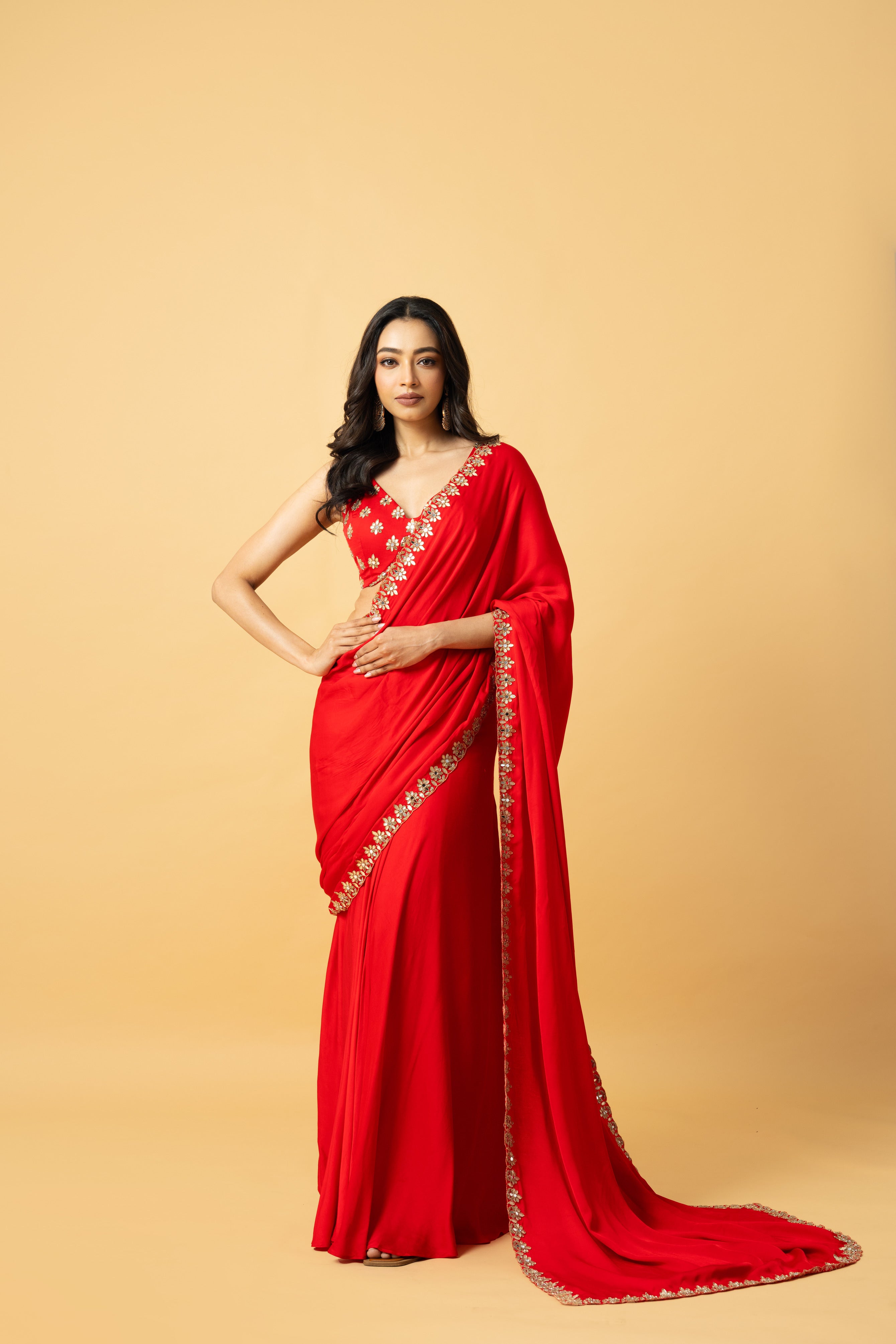 Red modal satin saree with a sleeveless hand-embroidered blouse and pre-draped style.