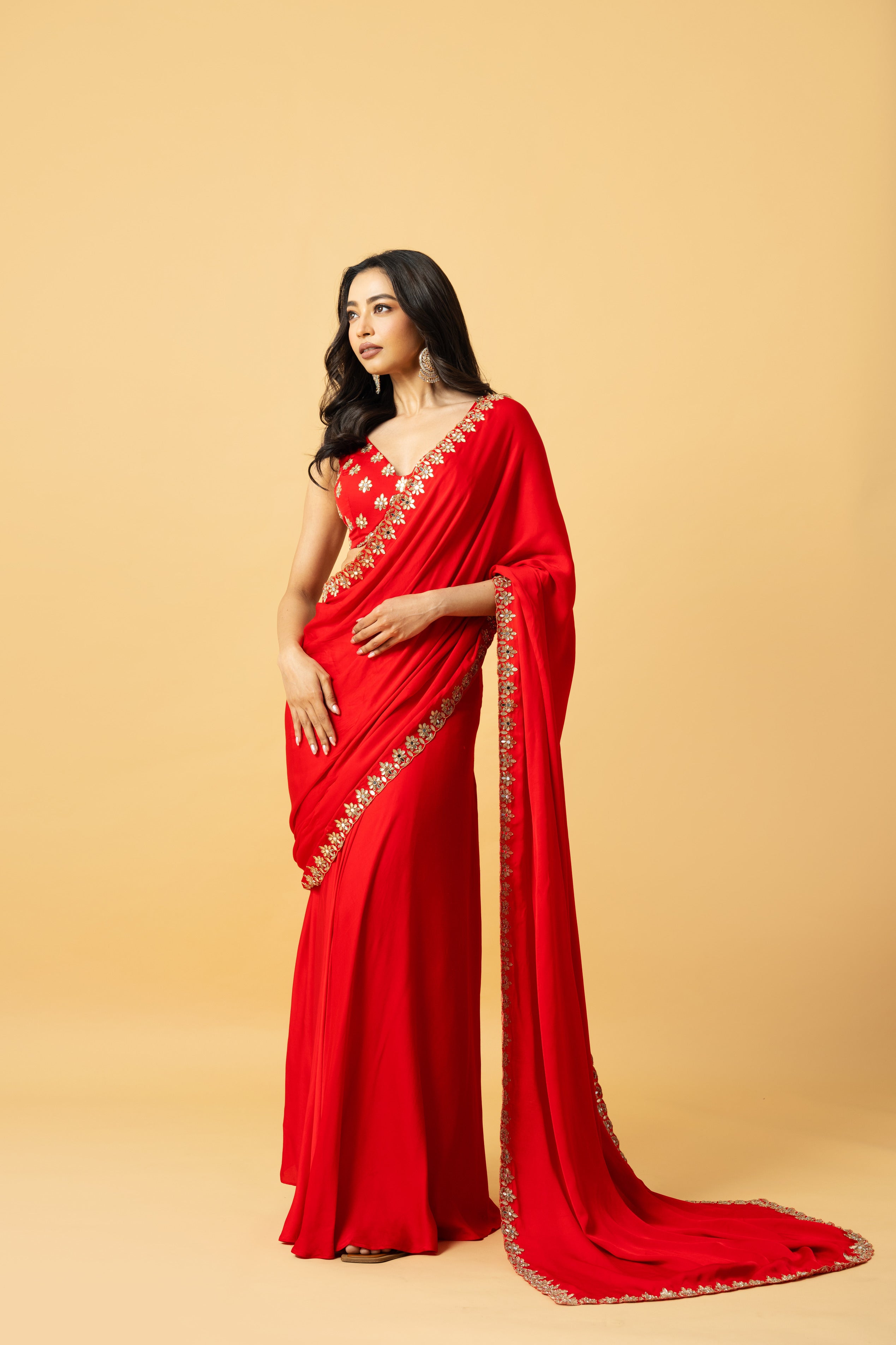 Red modal satin saree with a sleeveless hand-embroidered blouse and pre-draped style.