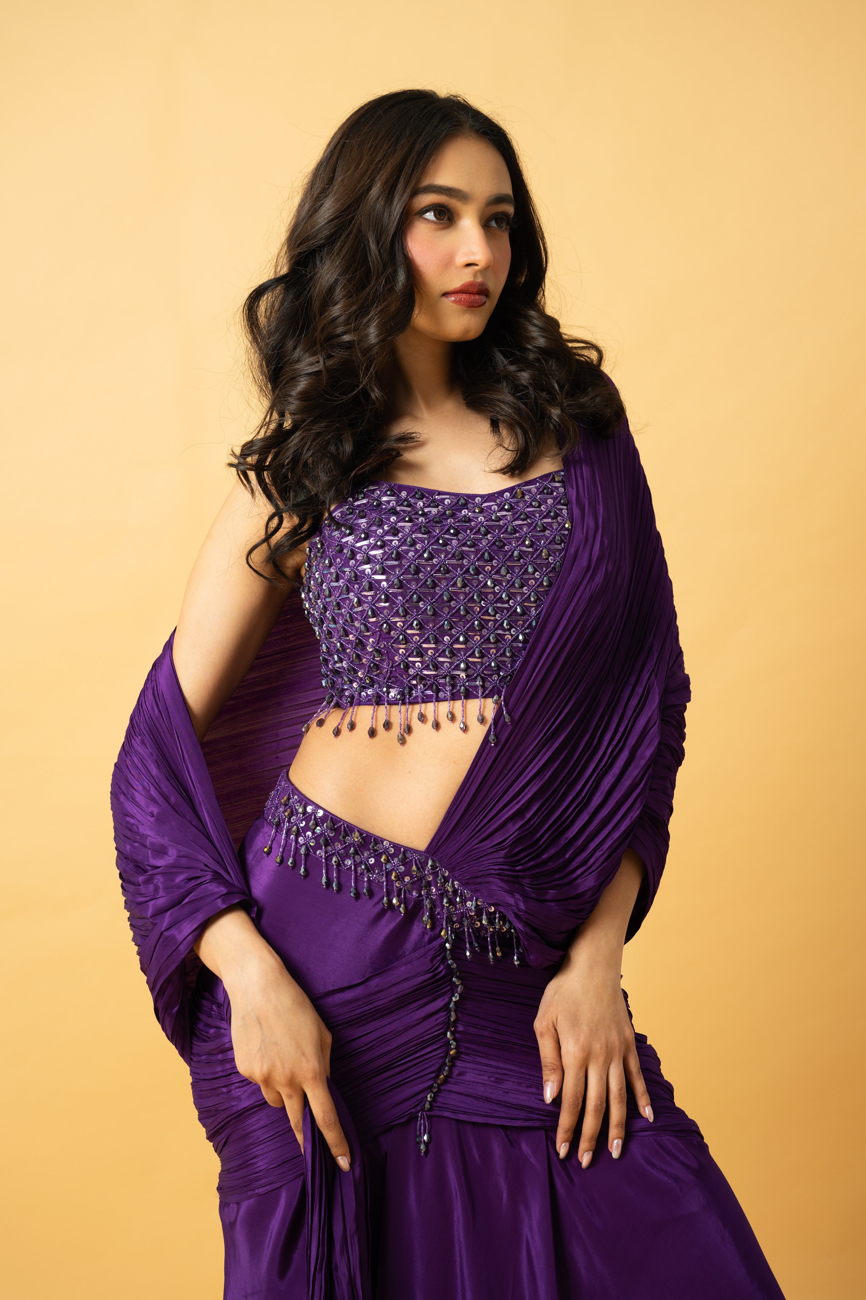 Violet crepe saree with hand-embroidered sleeveless blouse and pre-draped design.